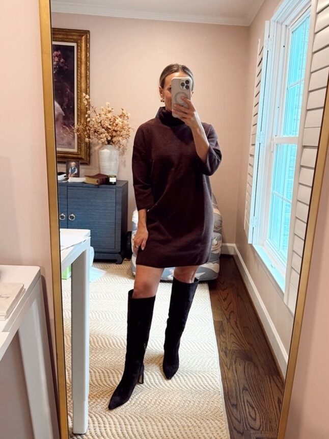 Woman taking a selfie while wearing a turtleneck dress with tall suede boots