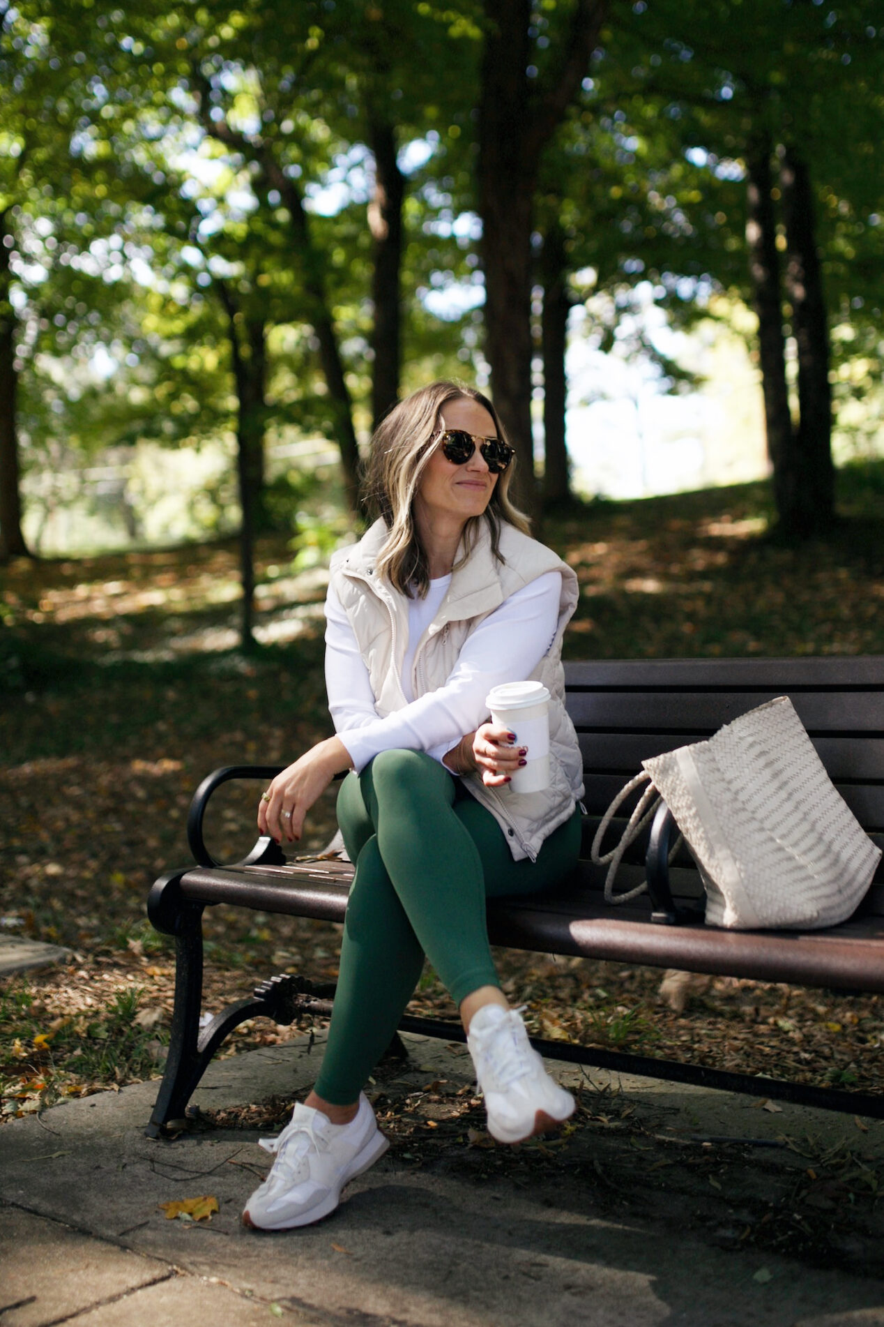Woman sitting on a bench holding a coffee cup in cute athleisure outfit