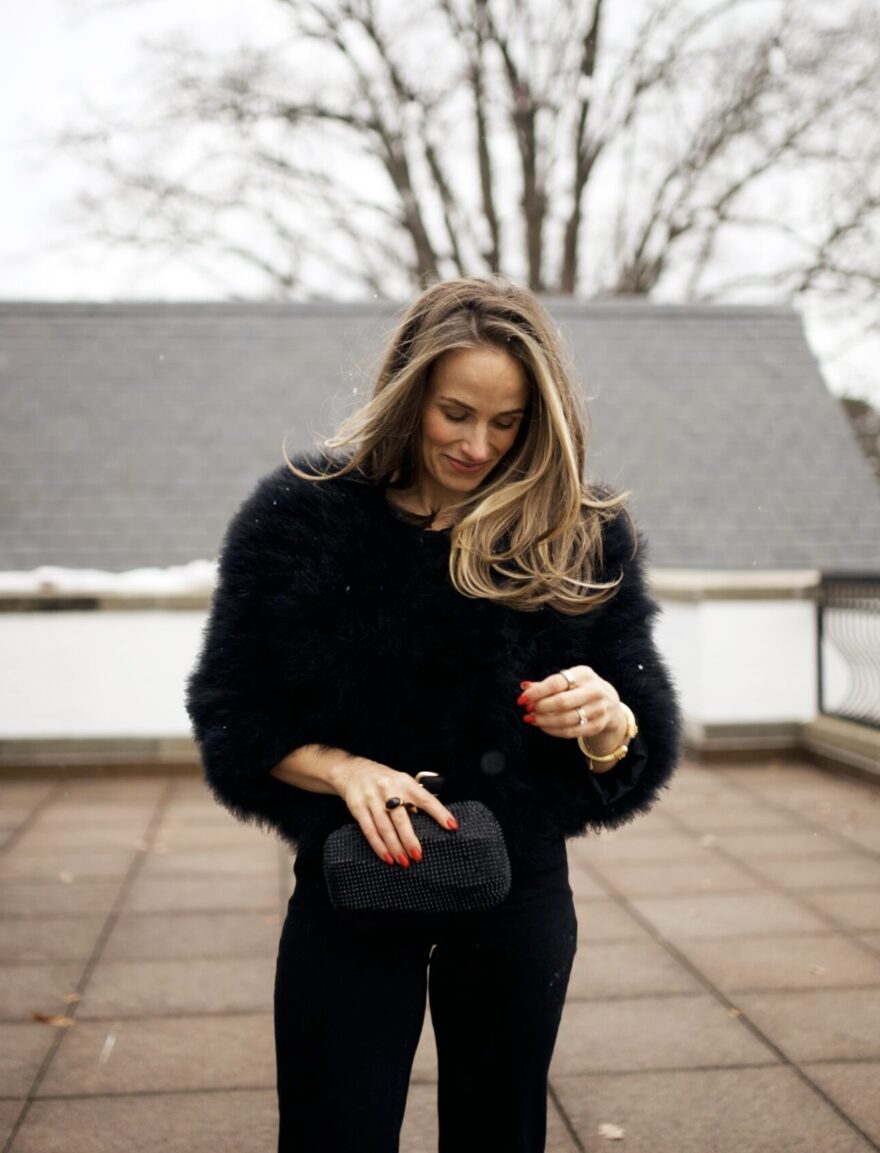 Woman wearing black fur jacket and pants for New Years Eve