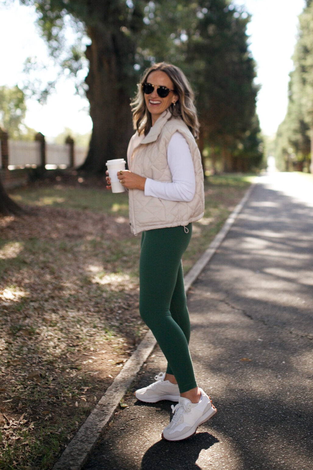Woman walking while wearing leggings, tennis shoes, and a vest