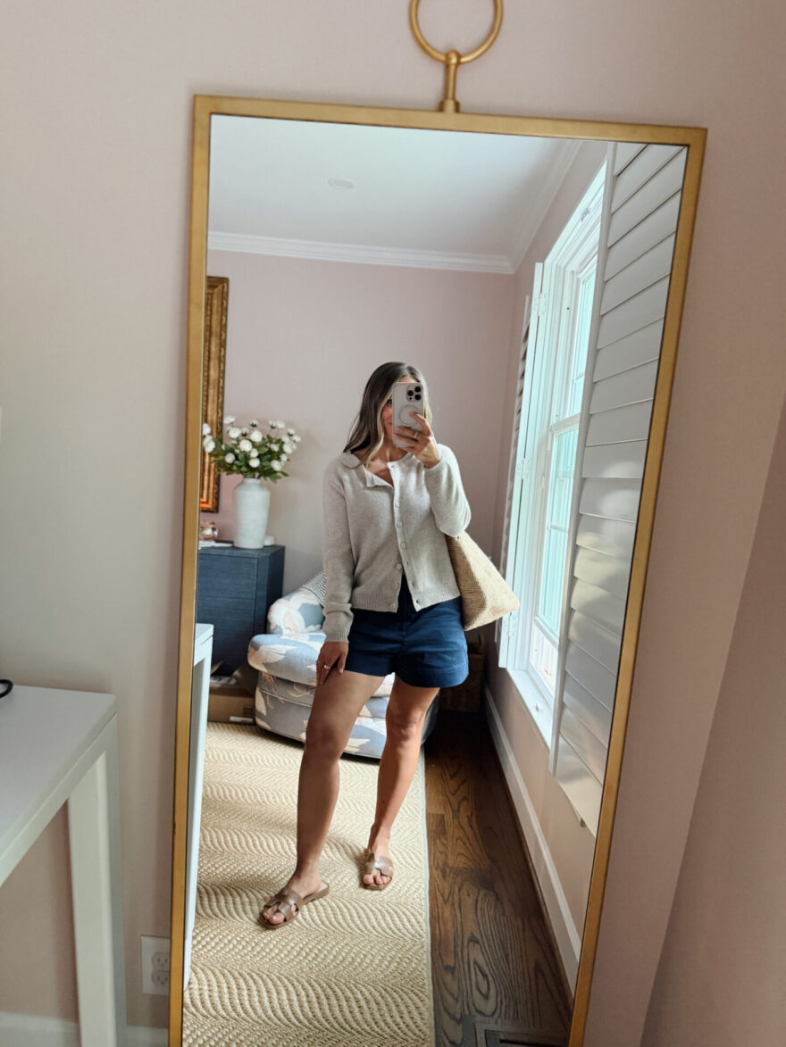 TeriLyn Adams wearing an oatmeal cardigan over navy shorts with a straw tote and sandals