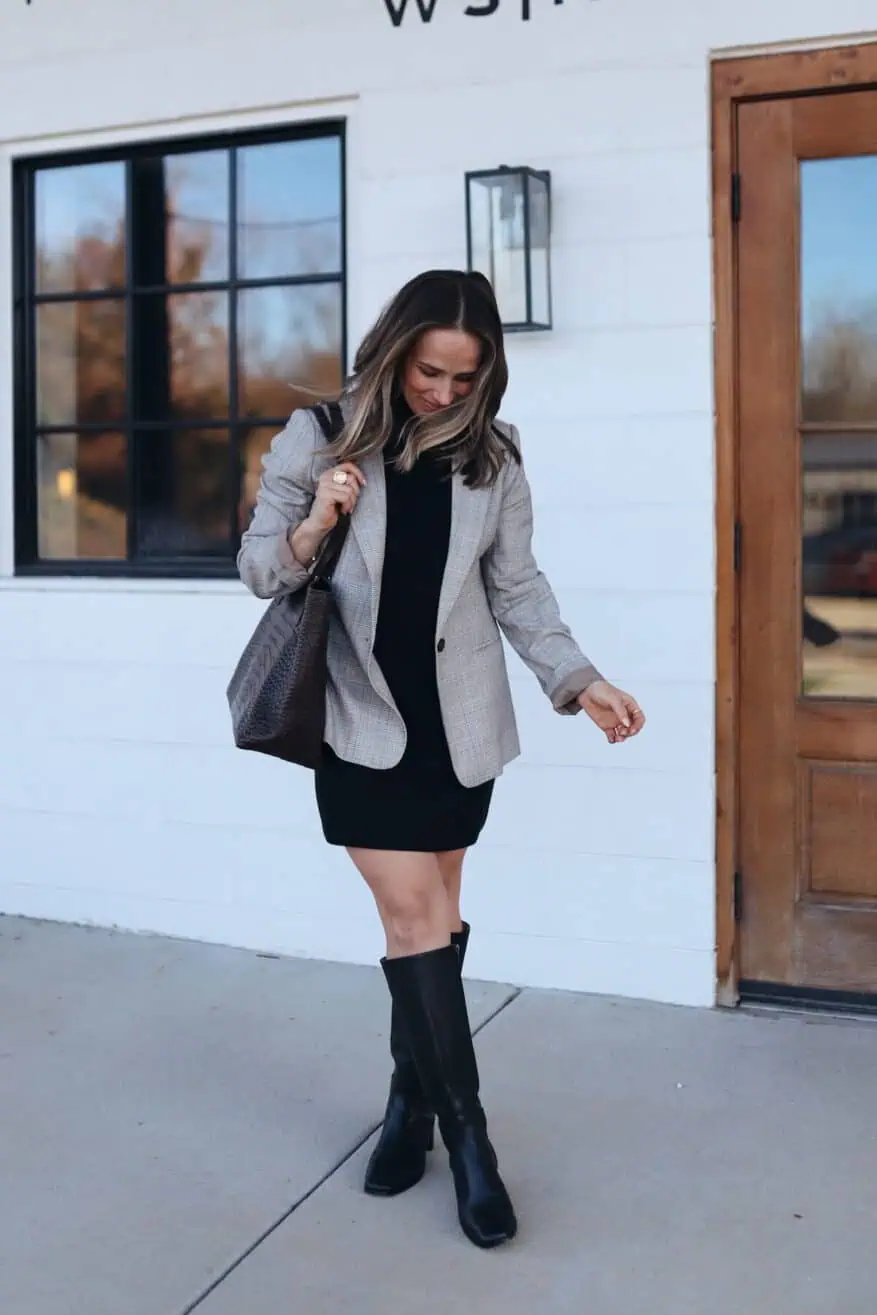 Woman standing outside wearing a black dress and well-fitted blazer with black purse