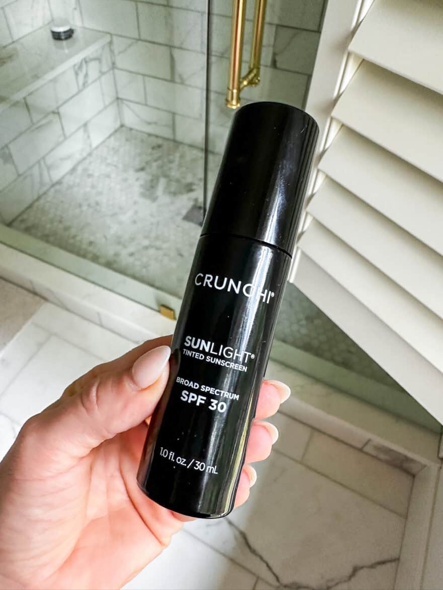 crunchi sunlight tinted moisturizer held in front of bathroom window