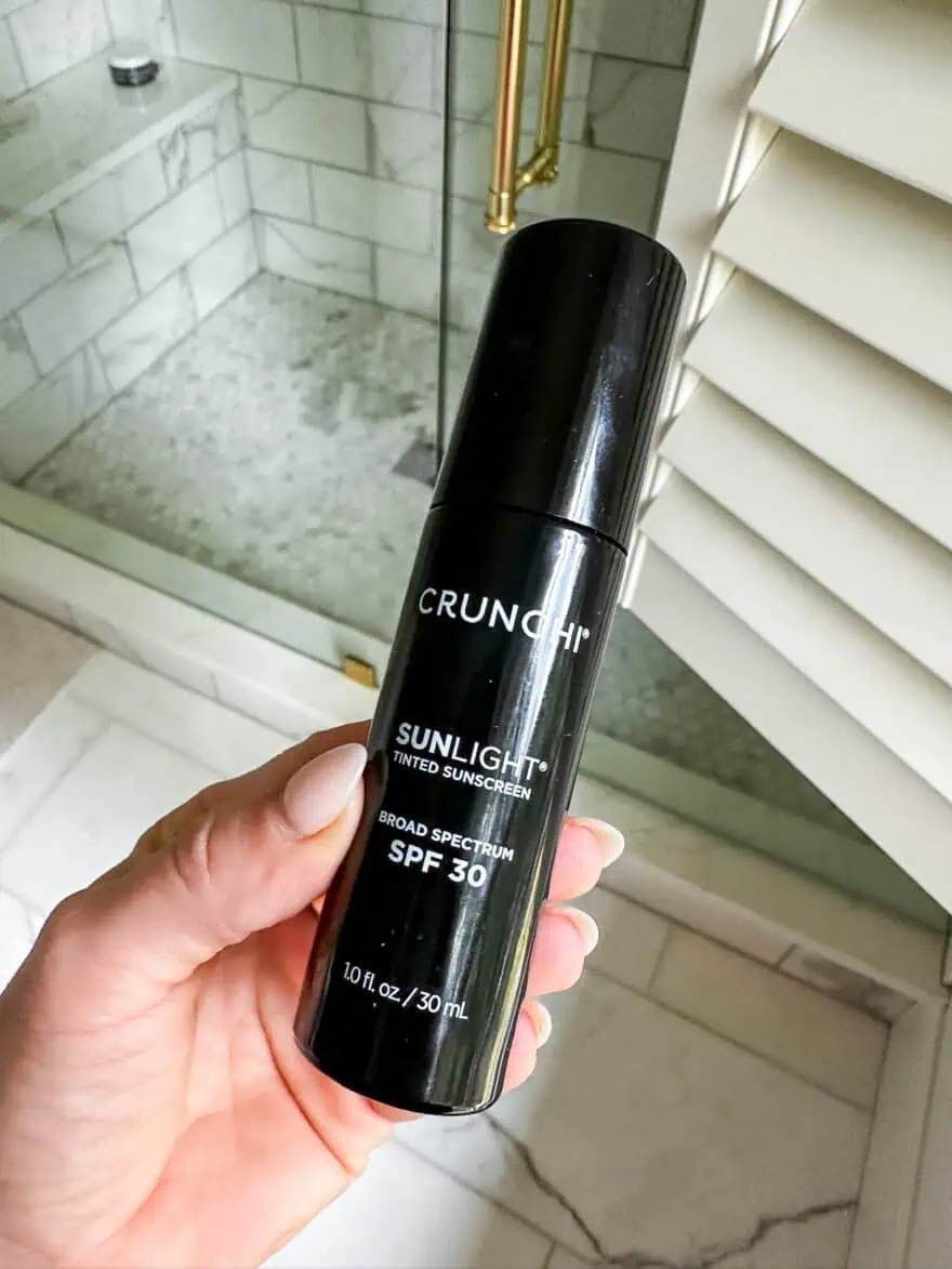 crunchi sunlight tinted moisturizer held in front of bathroom window