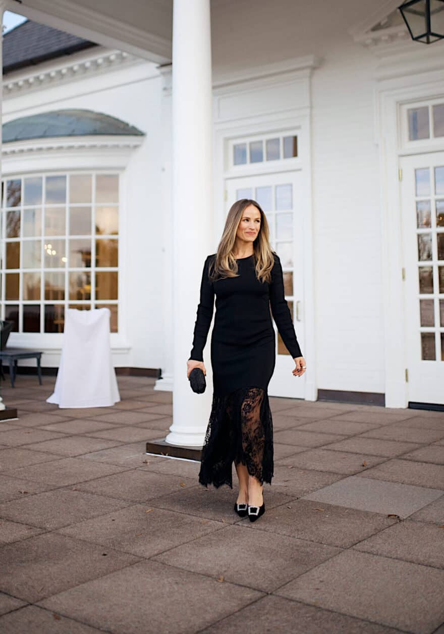 Woman walking and wearing a black formal dress with a black clutch and black kitten heels