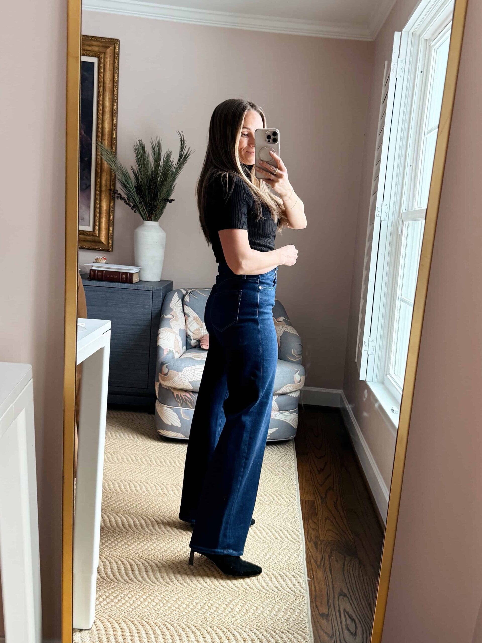 Woman showing side view of wide-leg jeans with a fitted top and pointy-toed heels