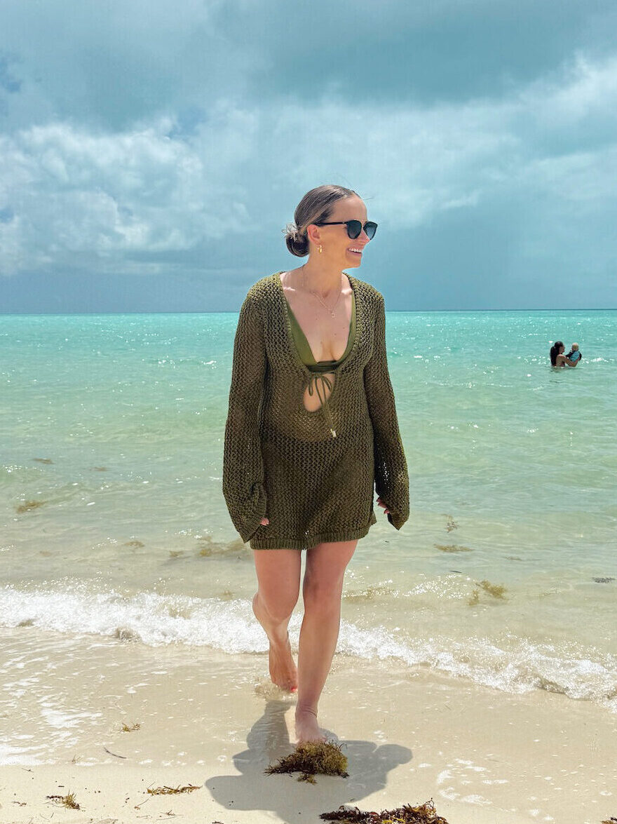 Woman walking out of ocean in green cover-up