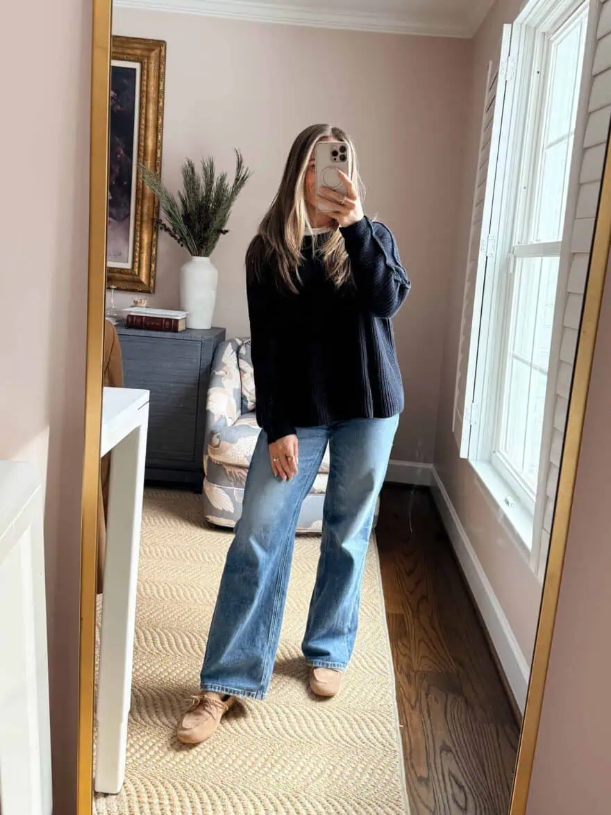 Woman wearing Quince denim with navy sweater and loafers