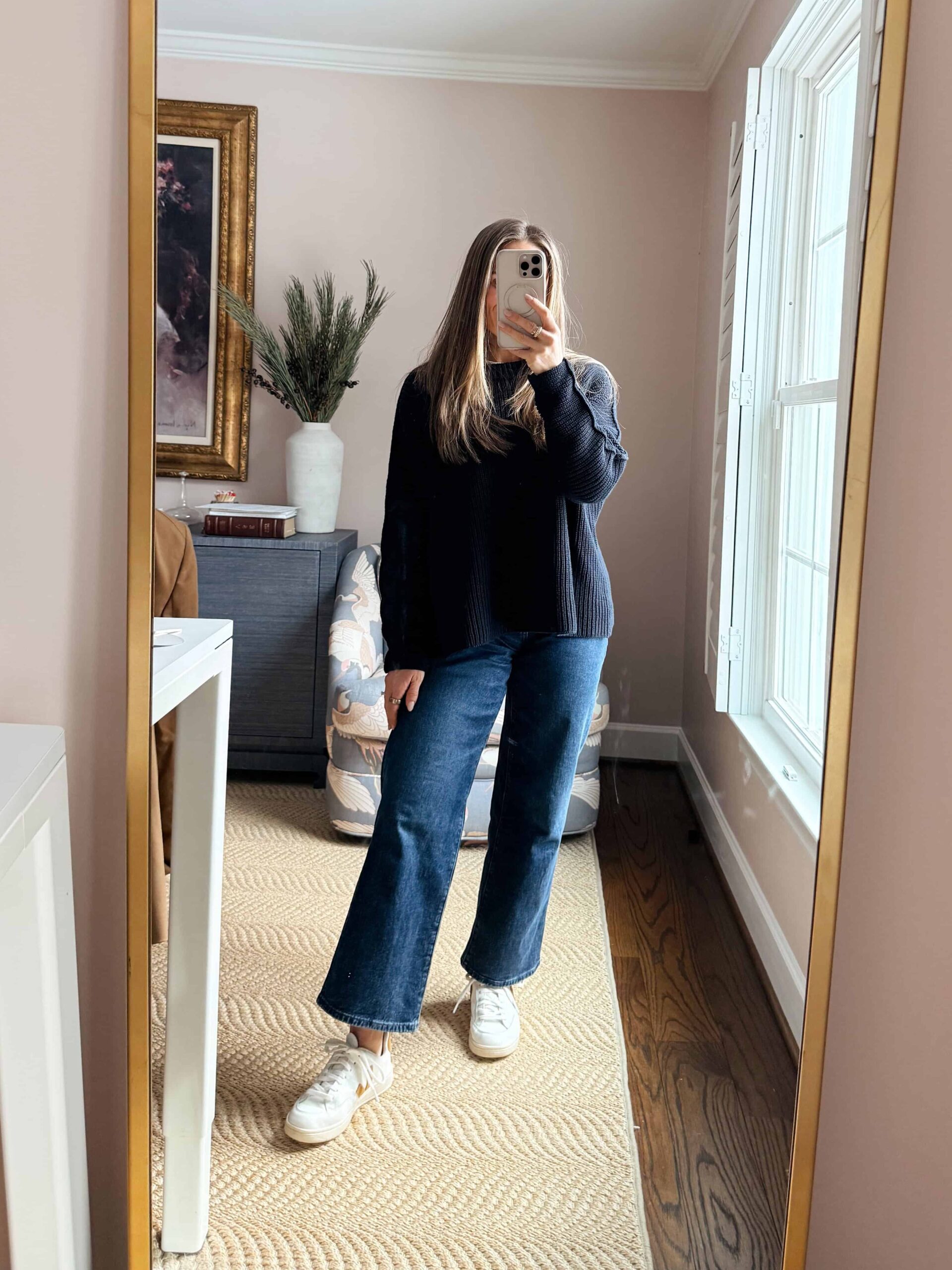 Woman wearing cropped wide-leg jeans with oversized navy sweater and sneakers
