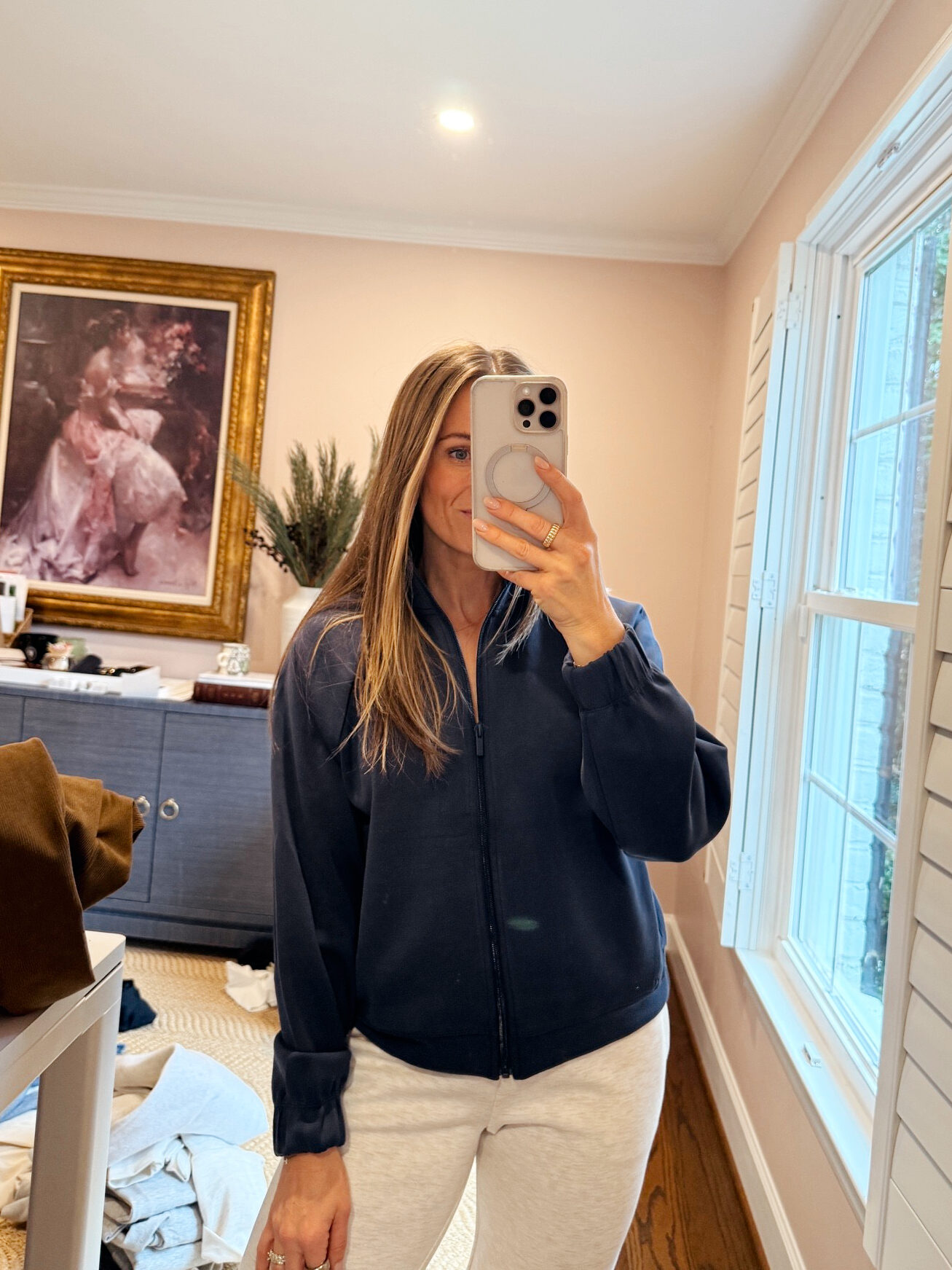 Woman taking picture wearing blue zip jacket and sweatpants