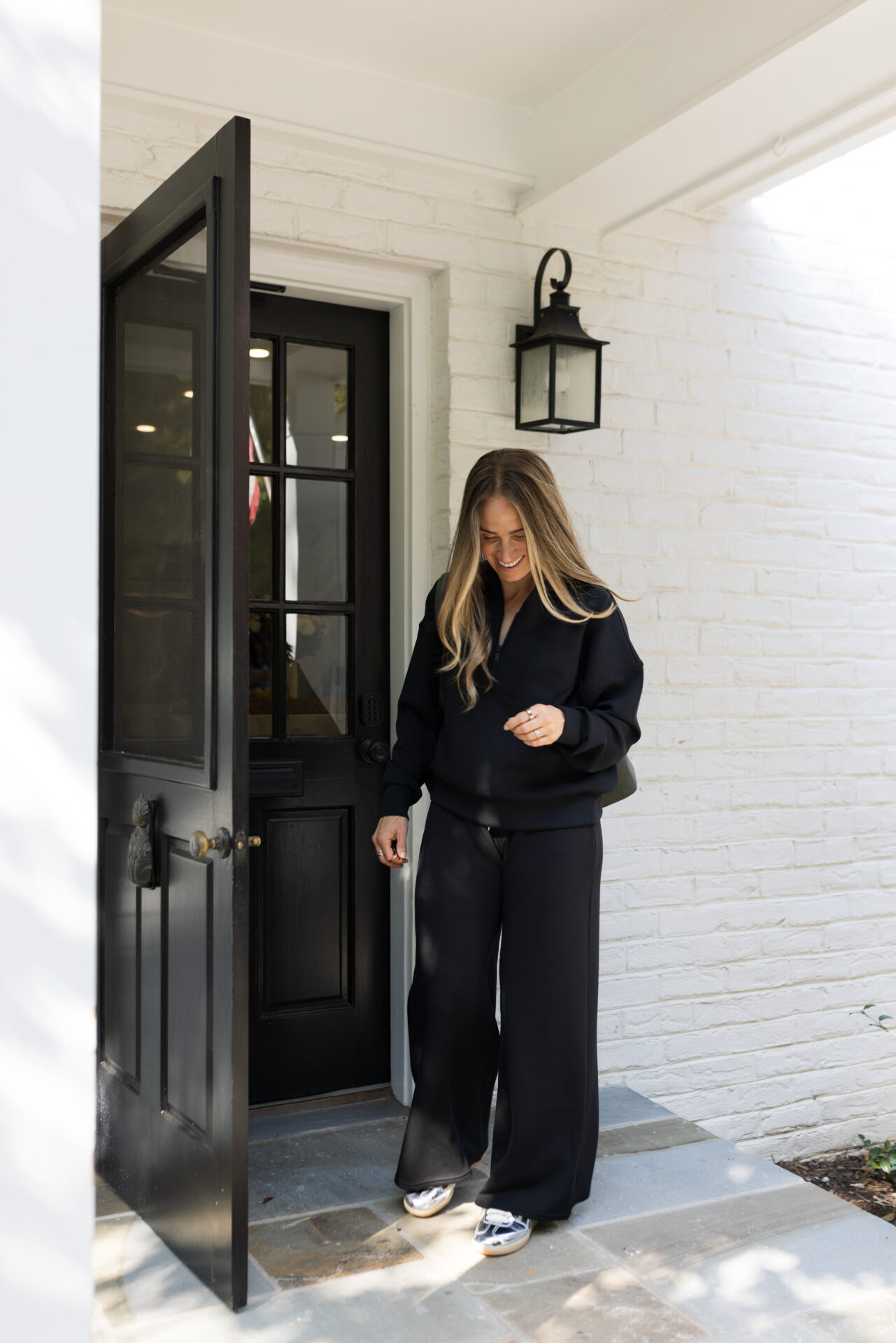TeriLyn Adams laughing while wearing the Spanx AirEssentials set at her front door