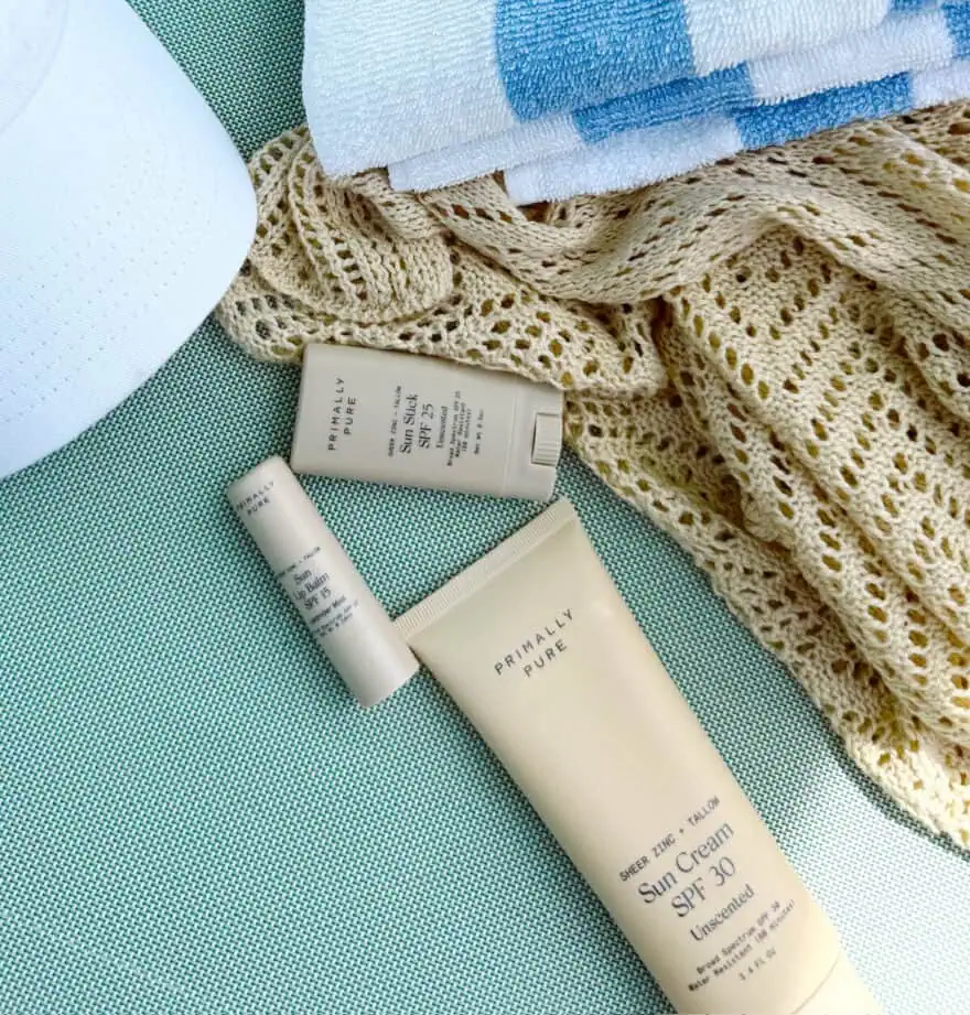 Primally Pure SPF sun cream on a lounge chair with cover up, towel, and hat