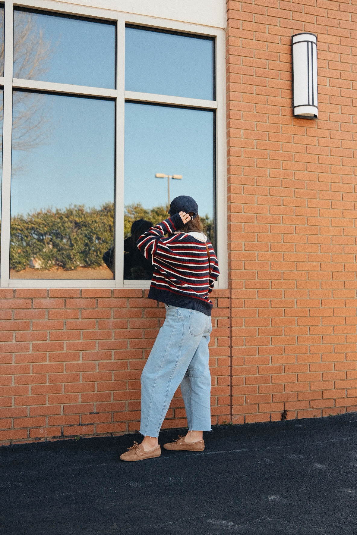 TeriLyn Adams wearing a striped sweater, cropped light blue jeans, and tan boat shoes outside a brick building