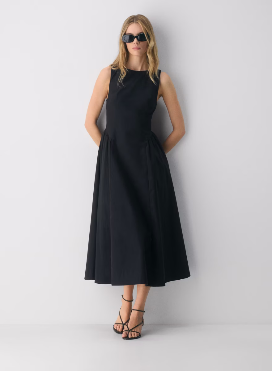 Woman wearing the Aritzia Tina poplin dress in navy with a sleeveless fitted bodice and full midi skirt