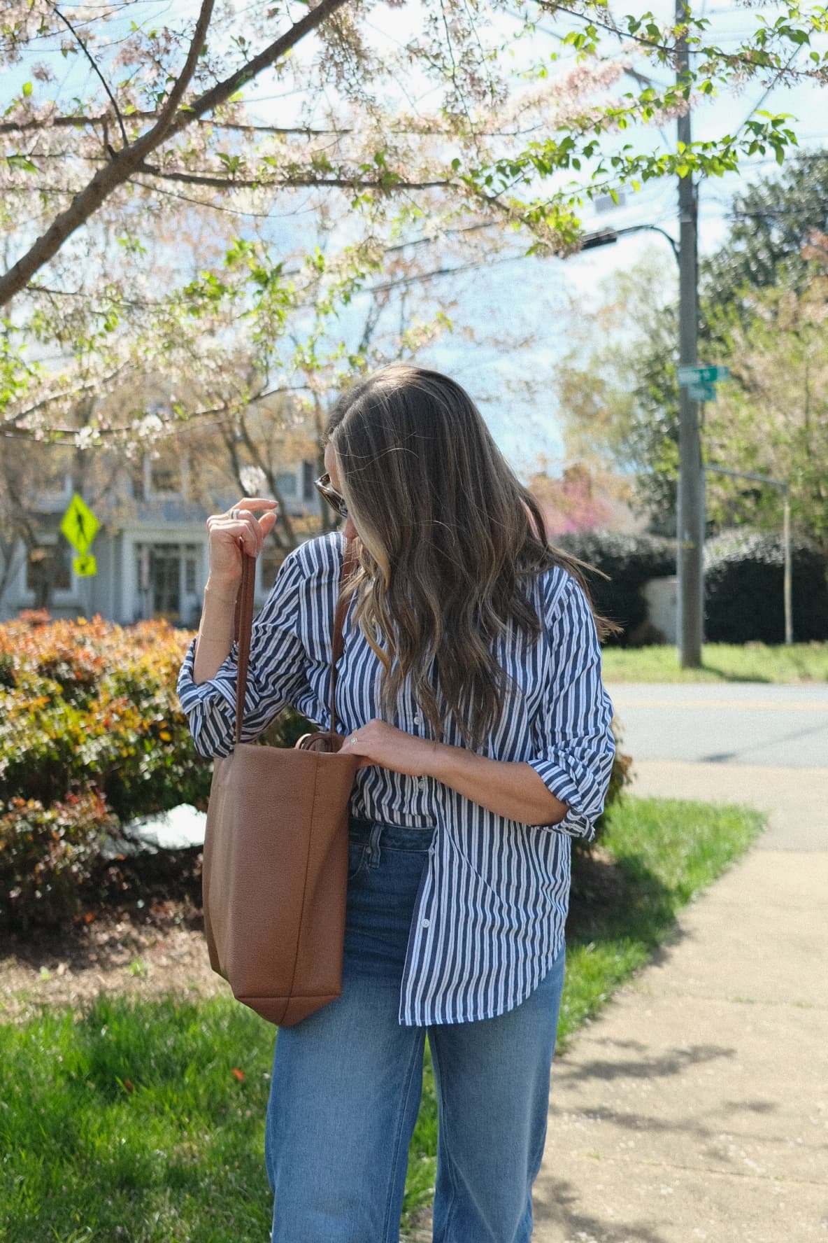 TeriLyn Adams with Cuyana brown leather tote bag wearing stripe shirt and jeans