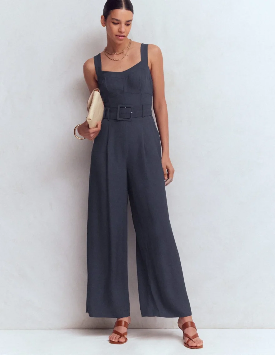 Woman wearing the Boden Boned Bodice Occasion jumpsuit in navy with a belted waist and wide-leg pants