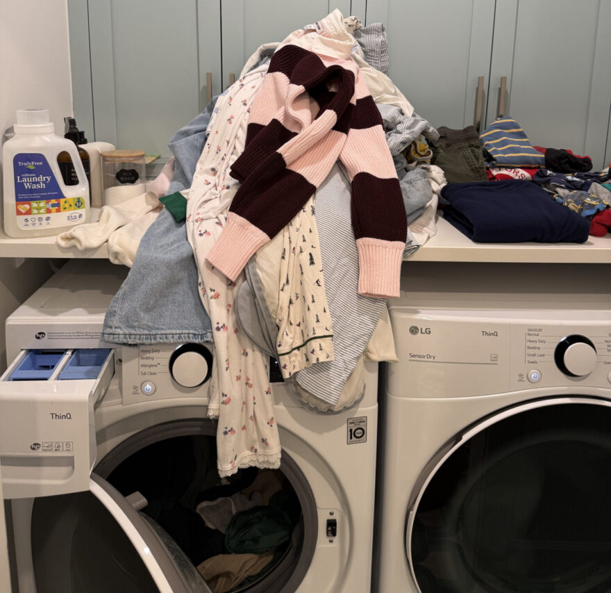Pile of folded laundry on washer and dryer, everyday help new moms need most.