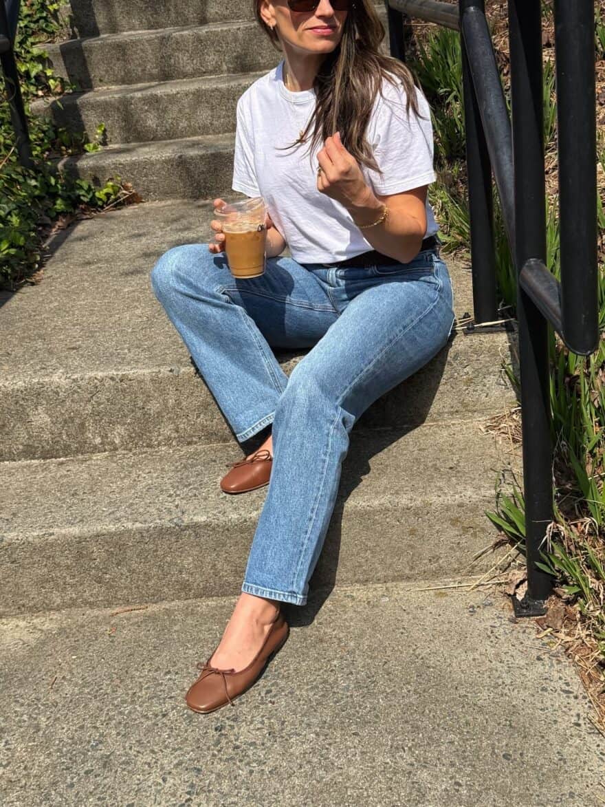 TeriLyn Adams sitting on cement steps wearing white tee and AYR straight leg jeans