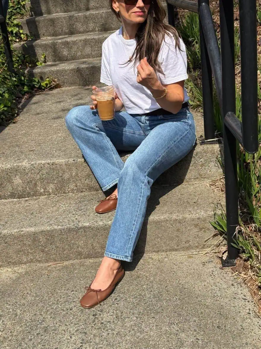 TeriLyn Adams sitting on cement steps wearing white tee and AYR straight leg jeans