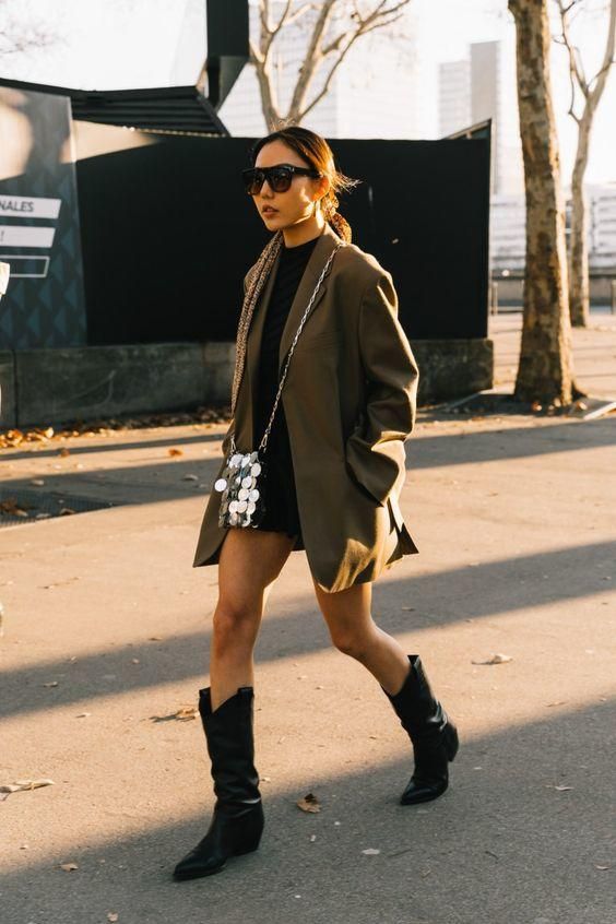 Woman wearing oversized blazer and cowboy boots walking on city street