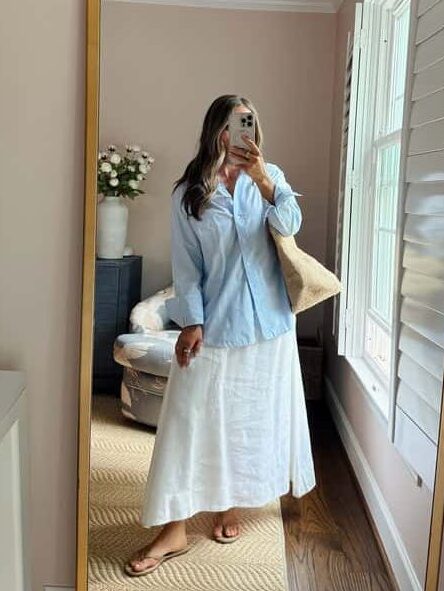 Terilyn adams taking a mirror selfie in a bright, modern room with casual outfit and handbag.