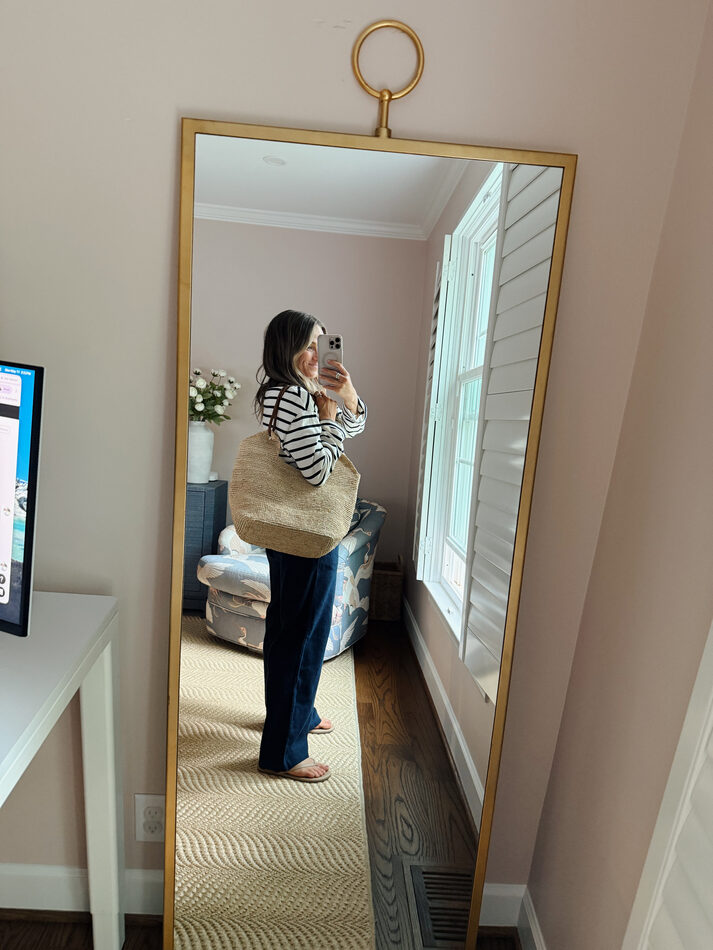 Terilyn adams taking a mirror selfie in a bright, modern room with casual outfit and handbag.