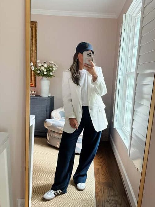 Terilyn adams taking a mirror selfie in a bright, modern room with casual outfit and handbag.