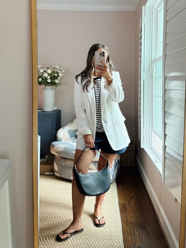 Terilyn adams taking a mirror selfie in a bright, modern room with casual outfit and handbag.