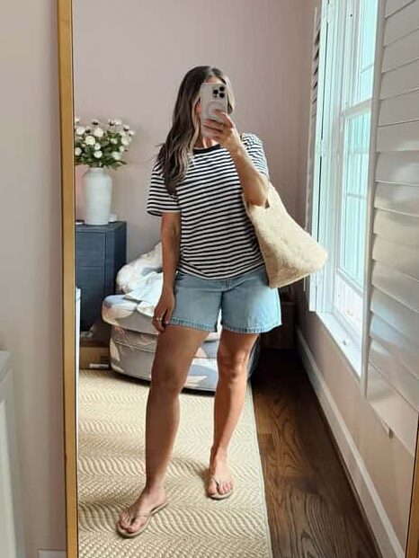 Terilyn adams taking a mirror selfie in a bright, modern room with casual outfit and handbag.