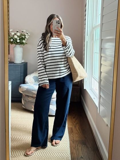 Terilyn adams taking a mirror selfie in a bright, modern room with casual outfit and handbag.