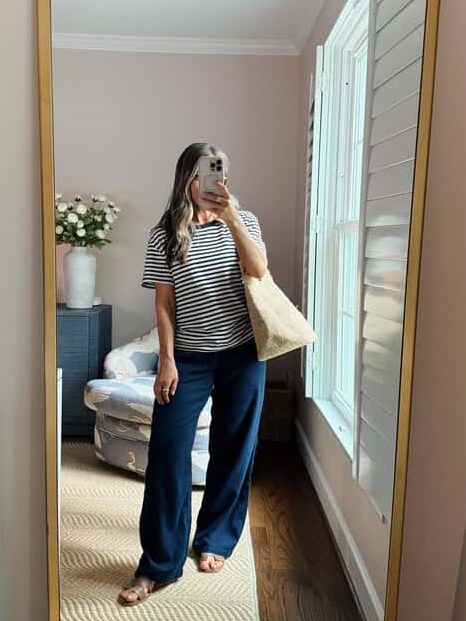 Terilyn adams taking a mirror selfie in a bright, modern room with casual outfit and handbag.
