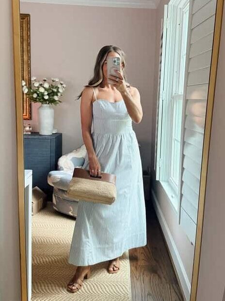Terilyn adams taking a mirror selfie in a bright, modern room with casual outfit and handbag.