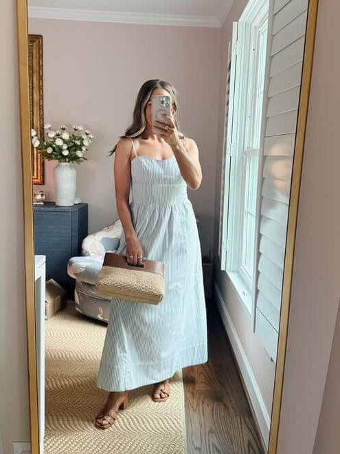 Terilyn adams taking a mirror selfie in a bright, modern room with casual outfit and handbag.