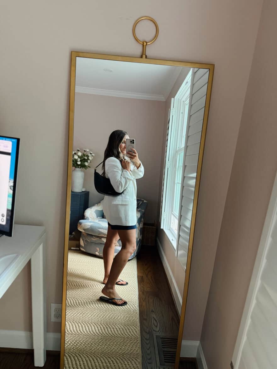 Terilyn adams taking a mirror selfie in a bright, modern room with casual outfit and handbag.