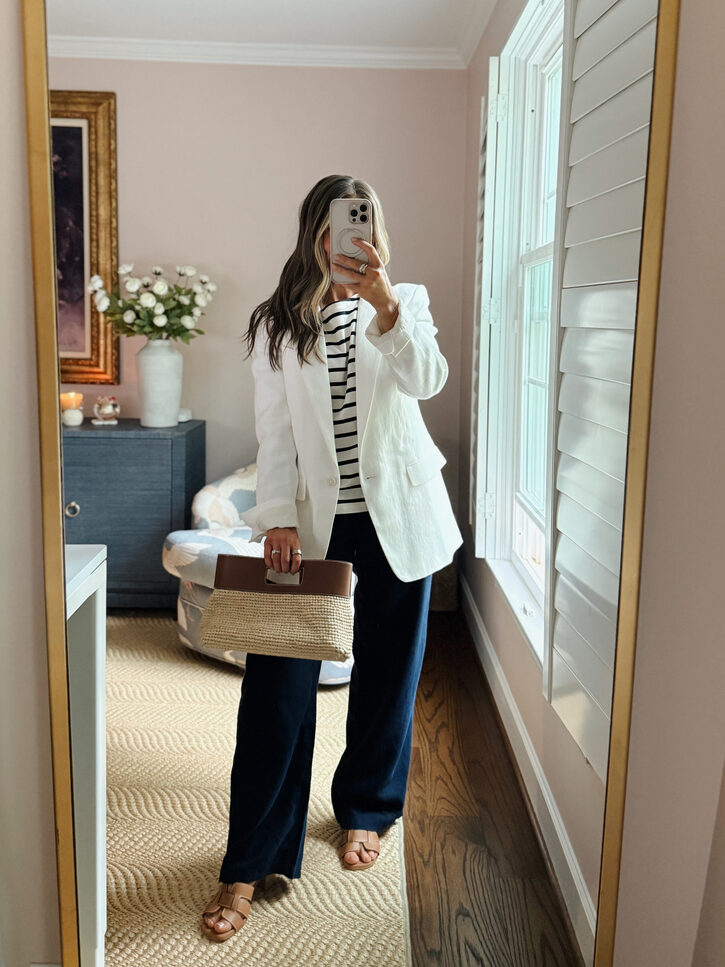 Terilyn adams taking a mirror selfie in a bright, modern room with casual outfit and handbag.