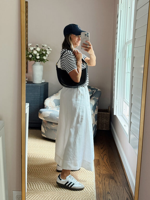 Terilyn adams taking a mirror selfie in a bright, modern room with casual outfit and handbag.