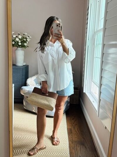 Terilyn adams taking a mirror selfie in a bright, modern room with casual outfit and handbag.