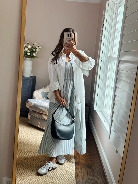 Terilyn adams taking a mirror selfie in a bright, modern room with casual outfit and handbag.