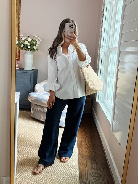 Terilyn adams taking a mirror selfie in a bright, modern room with casual outfit and handbag.