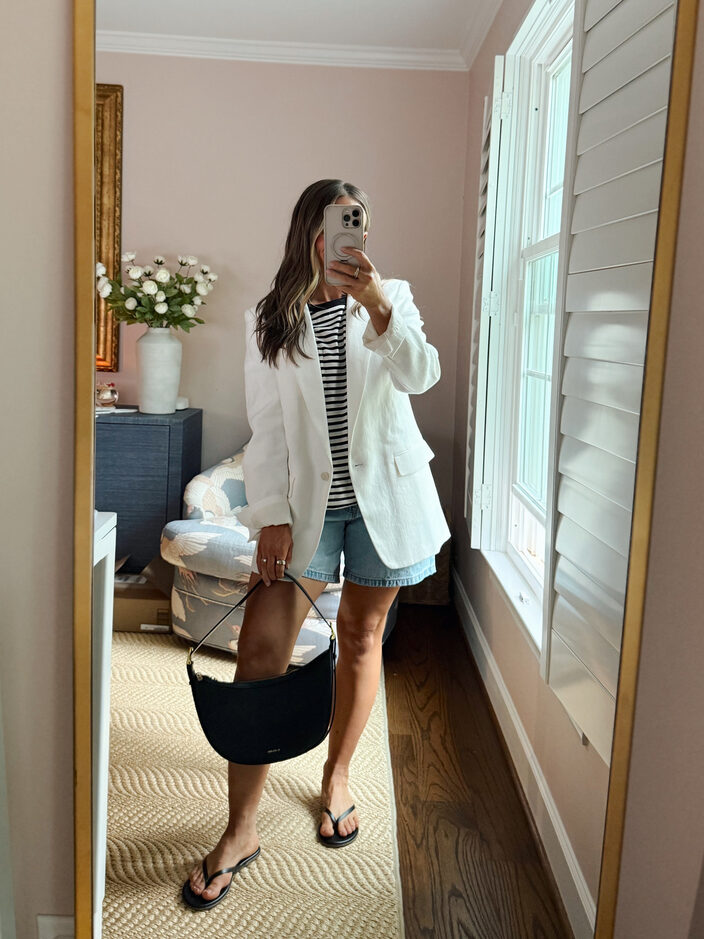 Terilyn adams taking a mirror selfie in a bright, modern room with casual outfit and handbag.