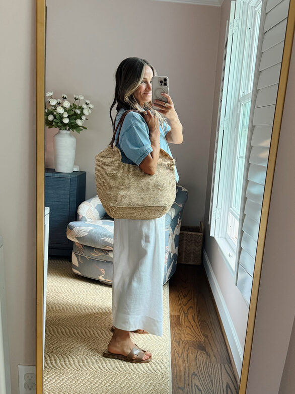 Terilyn adams taking a mirror selfie in a bright, modern room with casual outfit and handbag.
