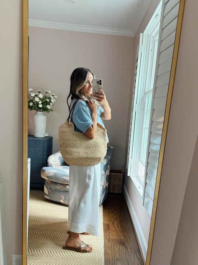 Terilyn adams taking a mirror selfie in a bright, modern room with casual outfit and handbag.