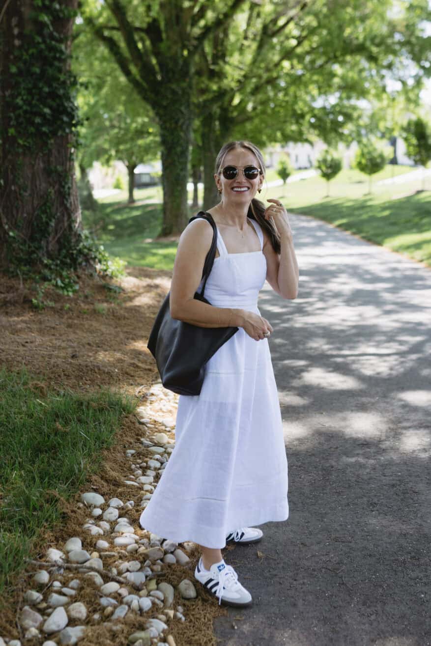 TeriLyn Adams walking in the park in a white linen dress with adidas sambas and tote bag