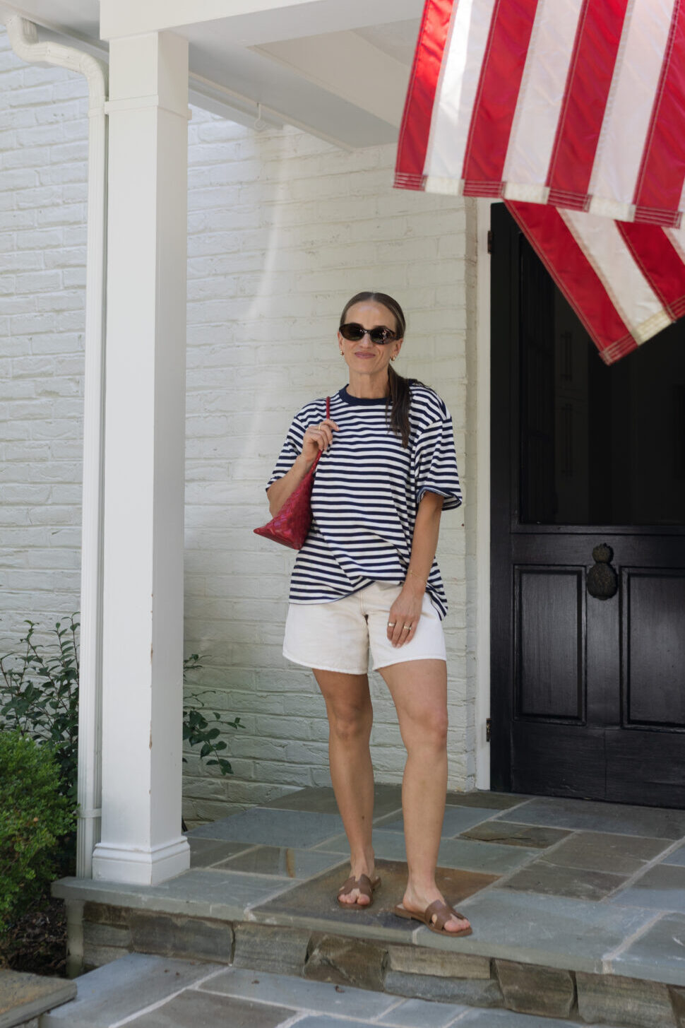 TeriLyn Adams wearing the Abercrombie High rise dad shorts with red purse and brown sandals.