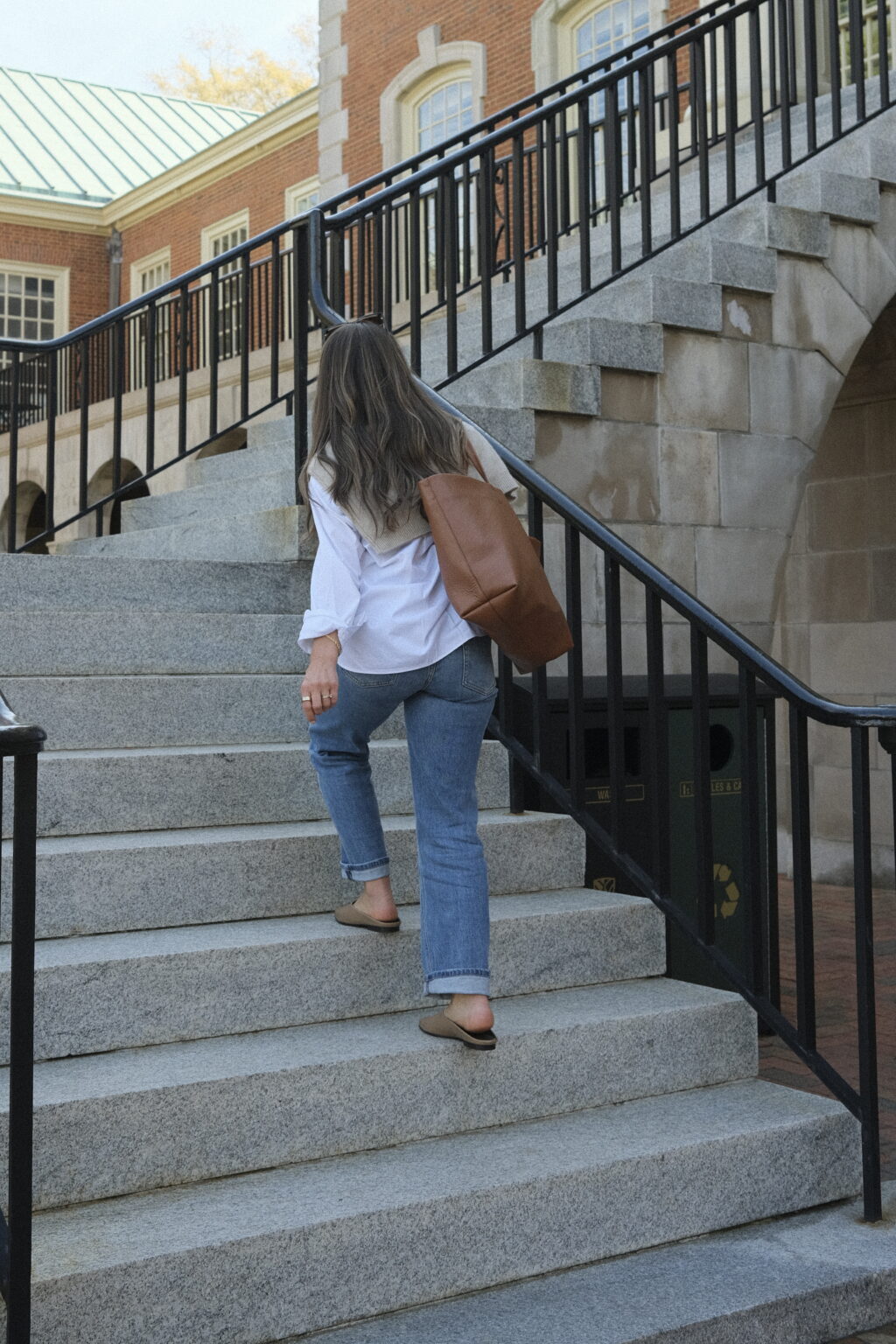 TeriLyn Adams walking up stairs in jeans and white button down with Cuyana leather tote.