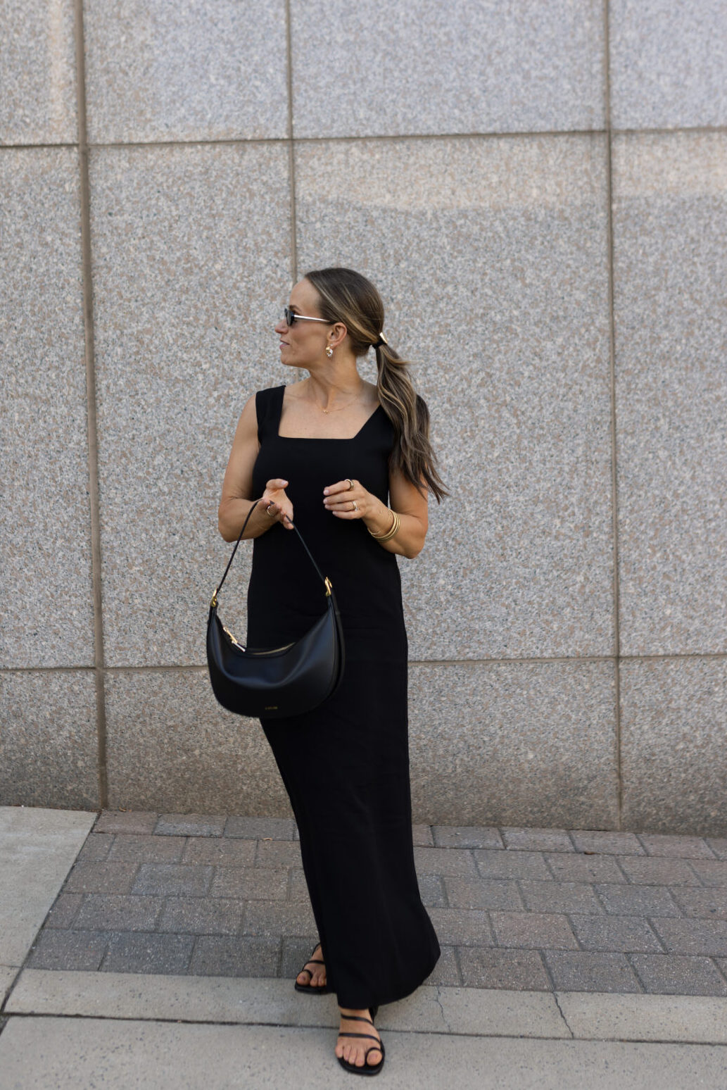 TeriLyn Adams wearing long black dress with black purse in front of building.