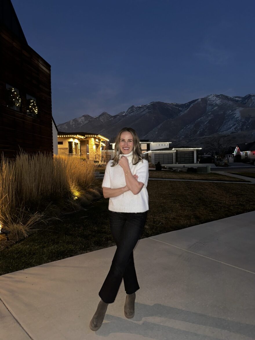 TeriLyn Adams wearing La Canadienne Wisdom booties with black flare jeans and a white sweater
