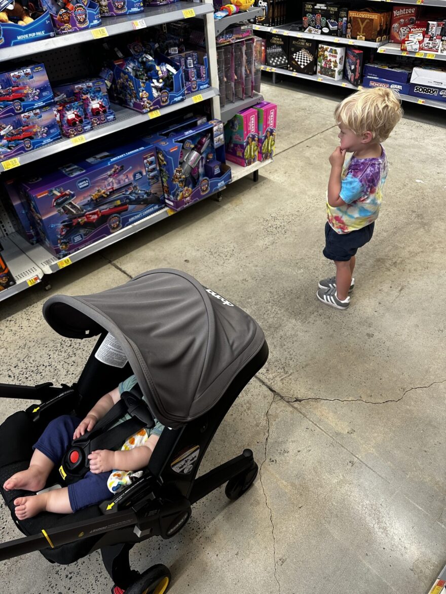 Toddler and baby in Doona stroller at store