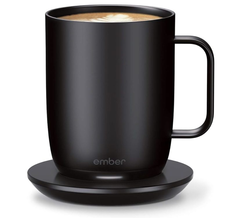 Ember smart mug with warming coaster, black, holding a latte, product shot.