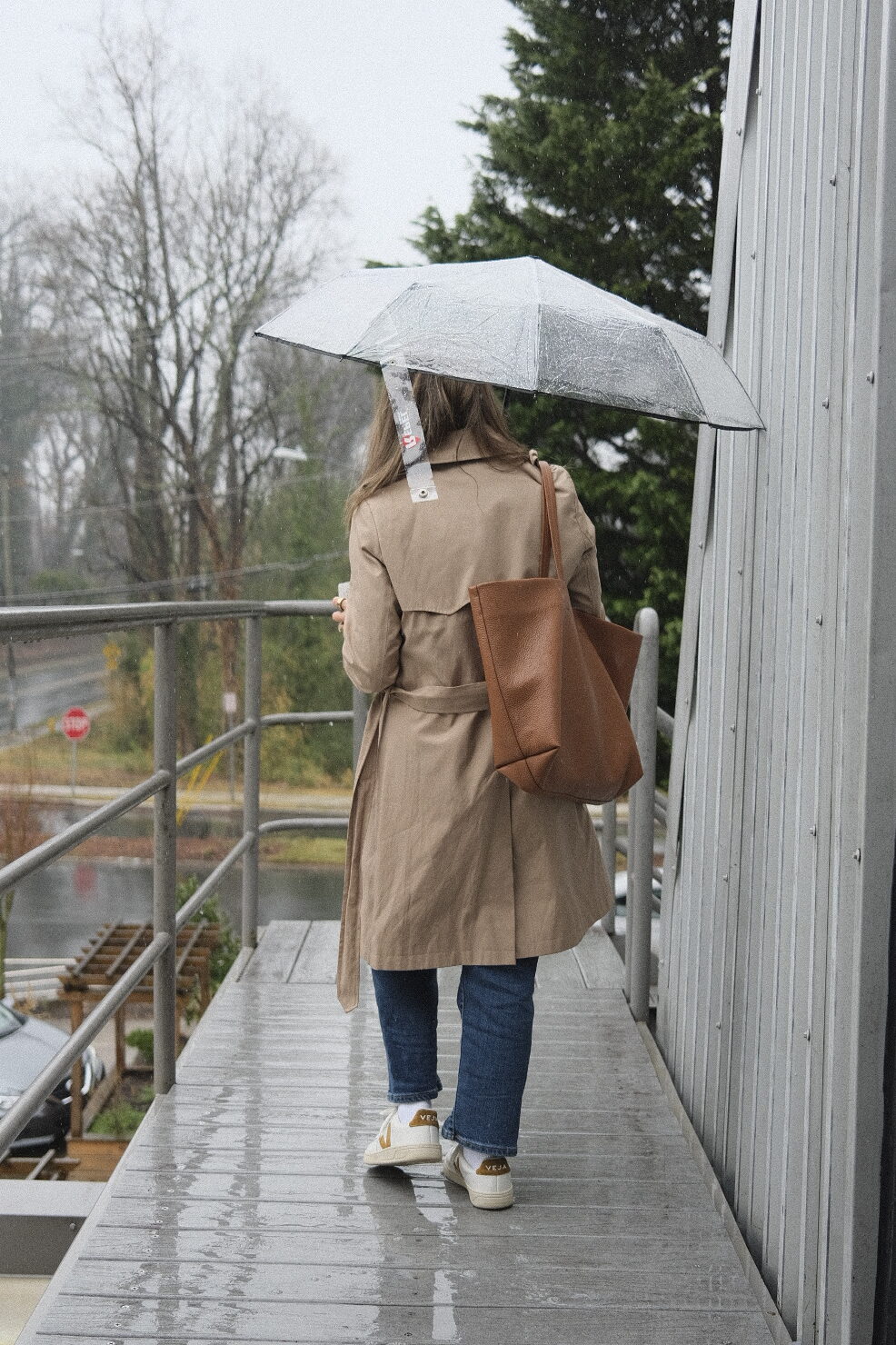 TeriLyn Adams walking in the rain with umbrella with Cuyana Classic Easy Tote over shoulder.
